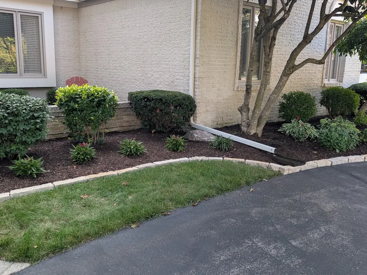 Mulched front bed with stone edging along a driveway