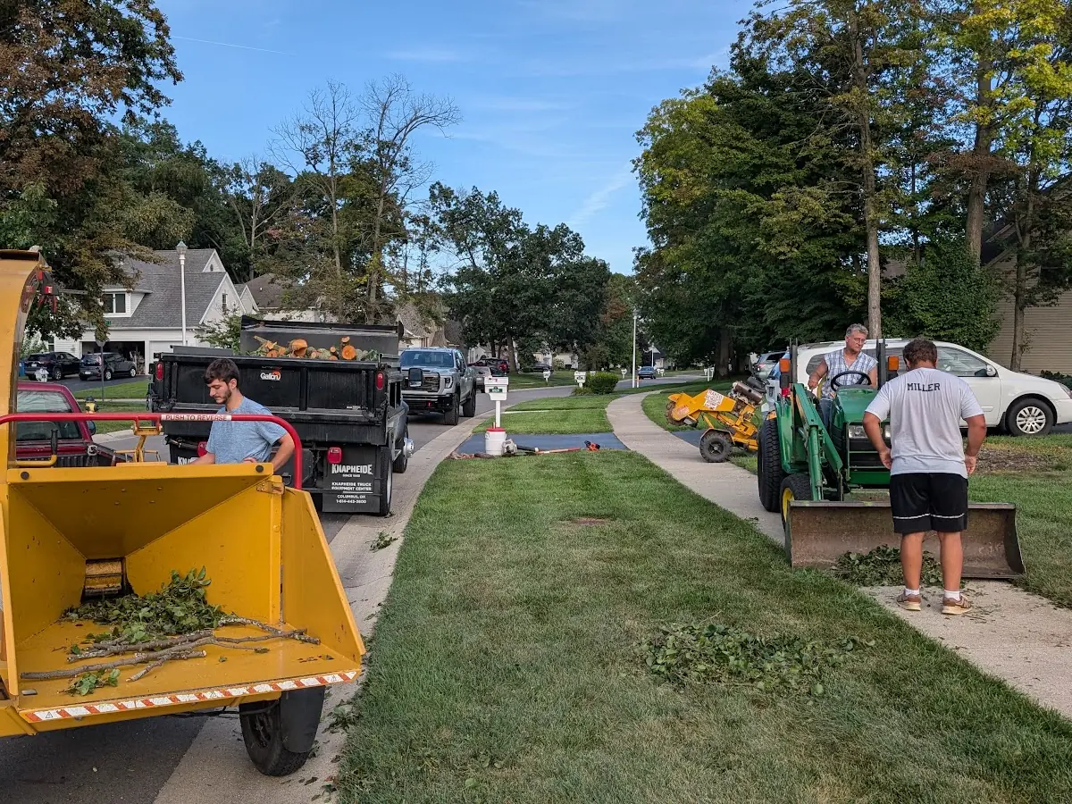 Wood chipper, dump truck and a small tractor with a crew on a residential street after tree work