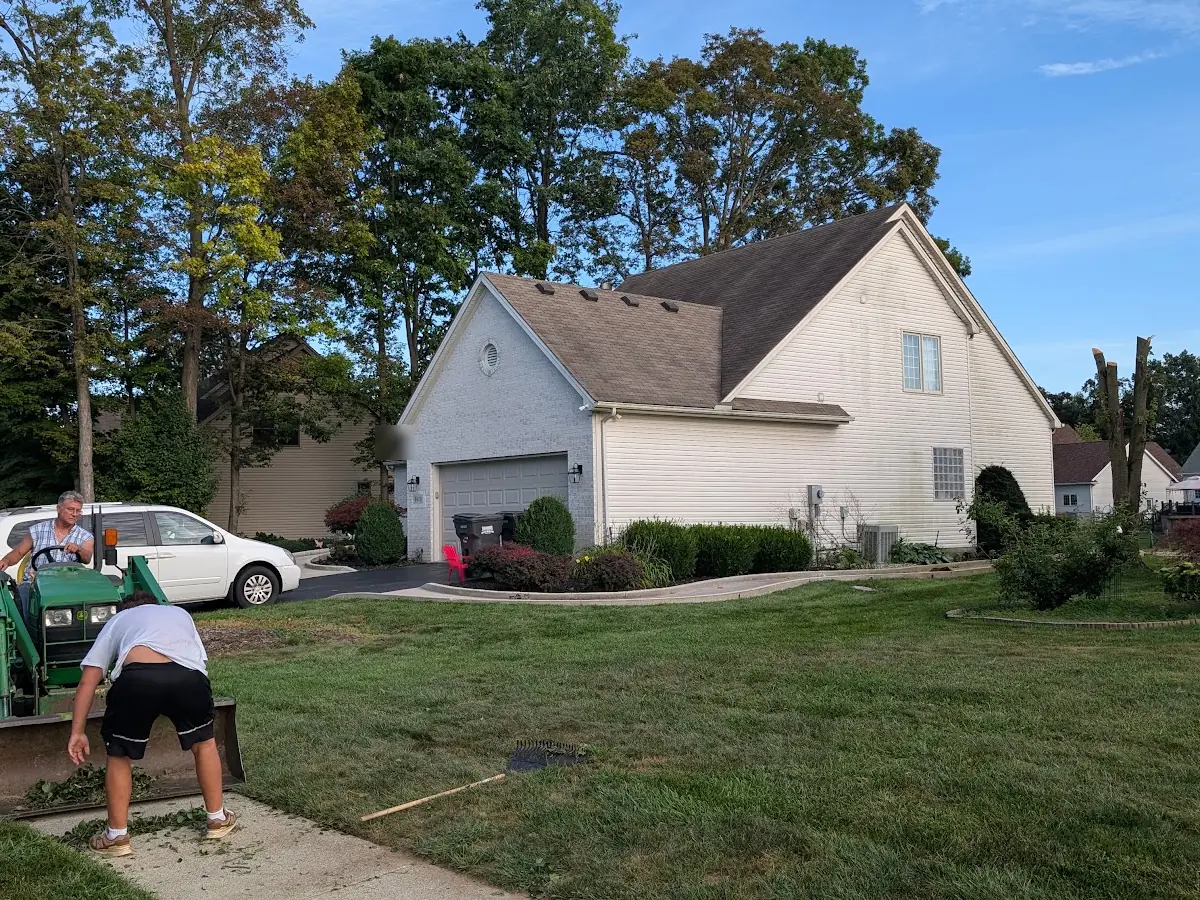 Crew with a small tractor and a stump grinder on a front lawn