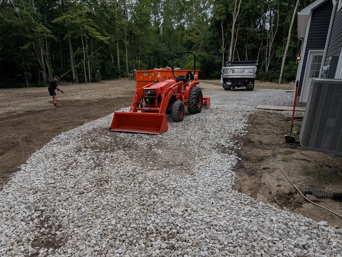 Orange tractor at the end of a long strip of crushed stone