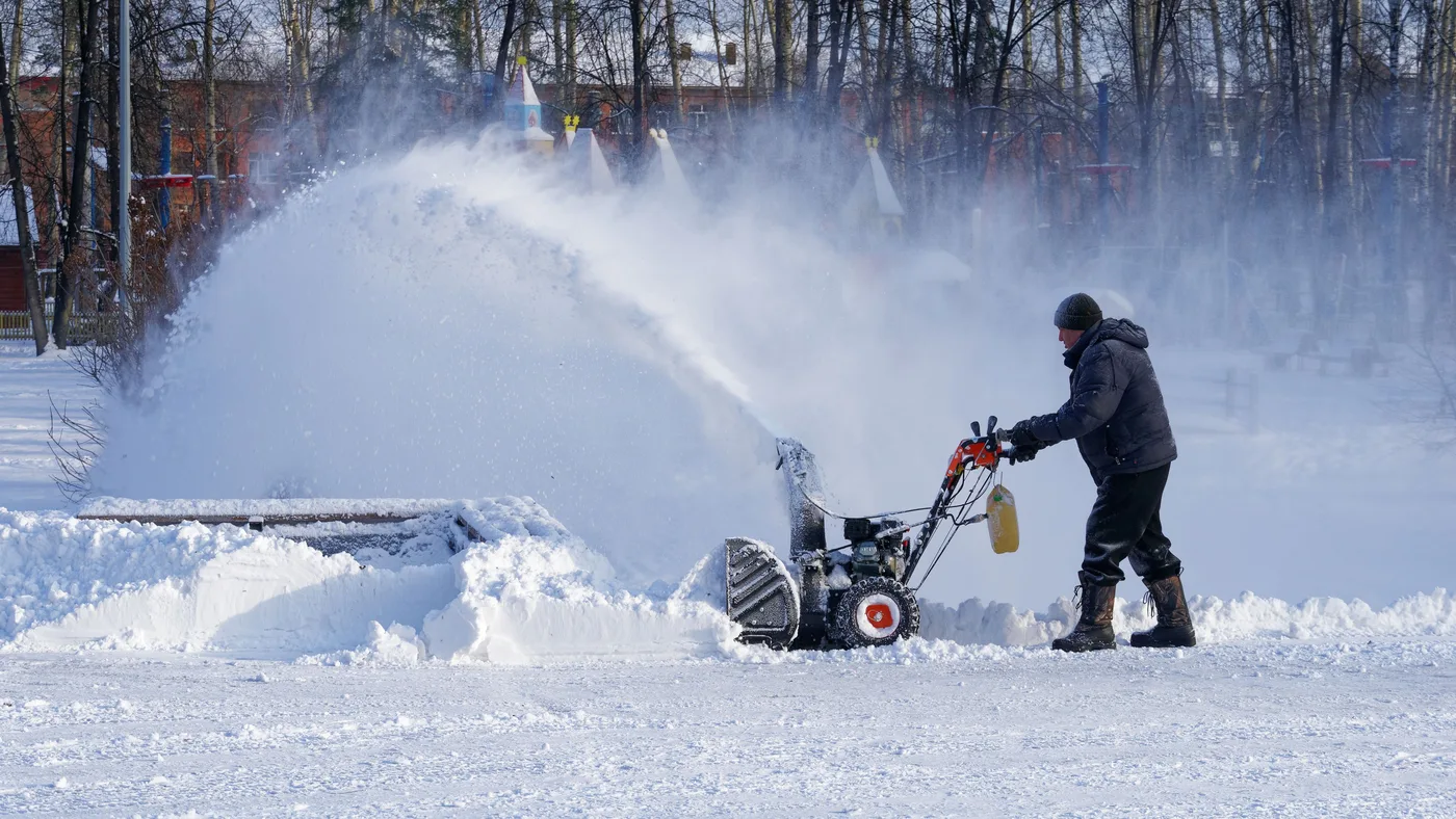 Person with a walk-behind snow blower throwing a big plume of snow